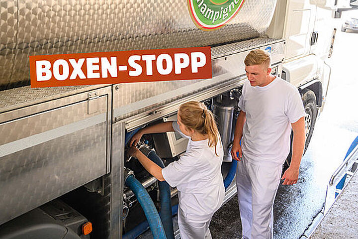 Motiv: Theresa und Norbert an einem Milch-Laster. Text: Boxen-Stopp.