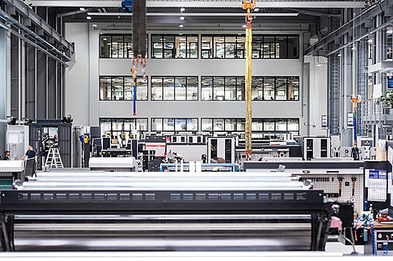 Blick in eine Industriewerkshalle mit sehr hohen Decken und großen Maschinen.  