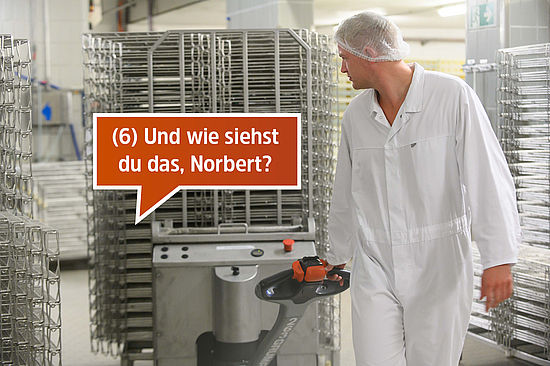 Motiv: Norbert fährt einen Elektrohubwagen mit Reifegestellen für den Käse. Text: 6. Und wie siehst du das, Norbert? 