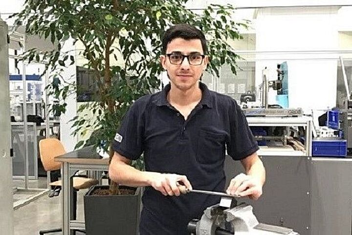 Industriemechaniker Youssef an einer Maschine in seinem Ausbildungsbetrieb.