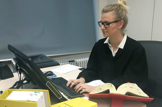 Eine junge Frau sitzt an einem Tisch mit einem Laptop. 